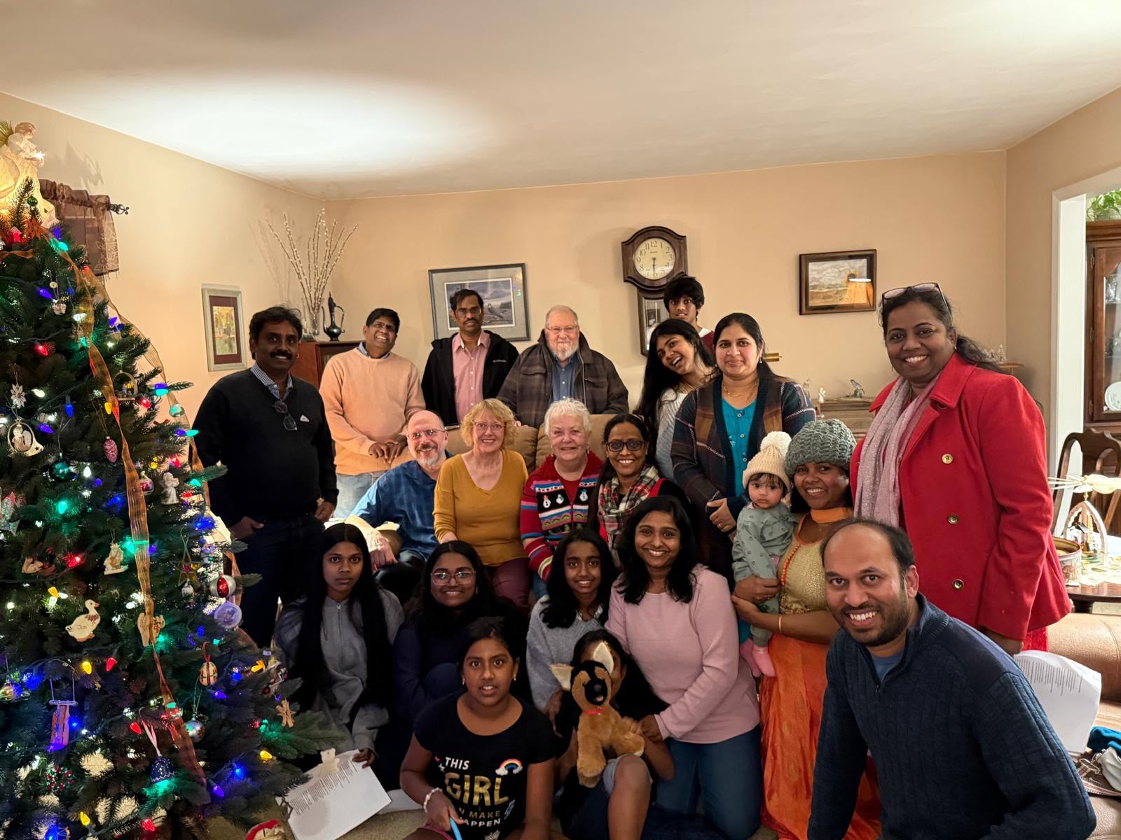 Fellowship members and friends gathered beside a decorated Christmas tree during a home visit